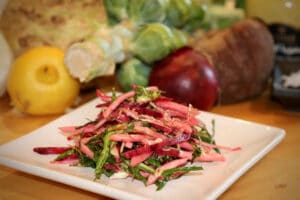photo of Christmas Coleslaw on a square white plant with raw vegetables in the background