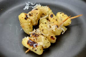 photo of two Gnocchi skewers on a black plate