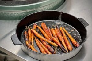photo of dirty Mountain Carrots in a cast iron skillet next to a bbq