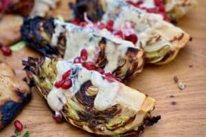 Charred Hispi Cabbage with Pomegranate and Tahini photo of charred Hispi Cabbage with Pomegranate and Tahini sliced on a baord
