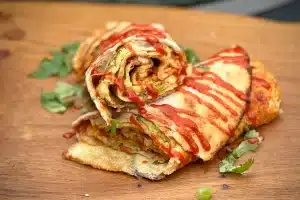 photo of Spicy Egg Wraps with chilli sauce drizzle on a board