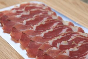photo of Home cured cold smoked bacon sliced on a silver tray