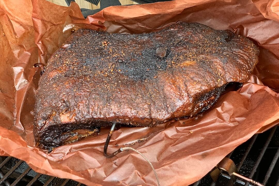 Photo of british BBQ brisket sitting on pink paper on a Big Green Egg